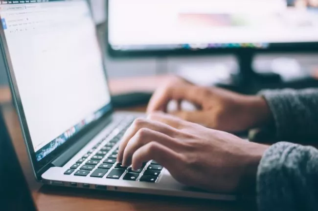 Stock image of a man typing on a laptop