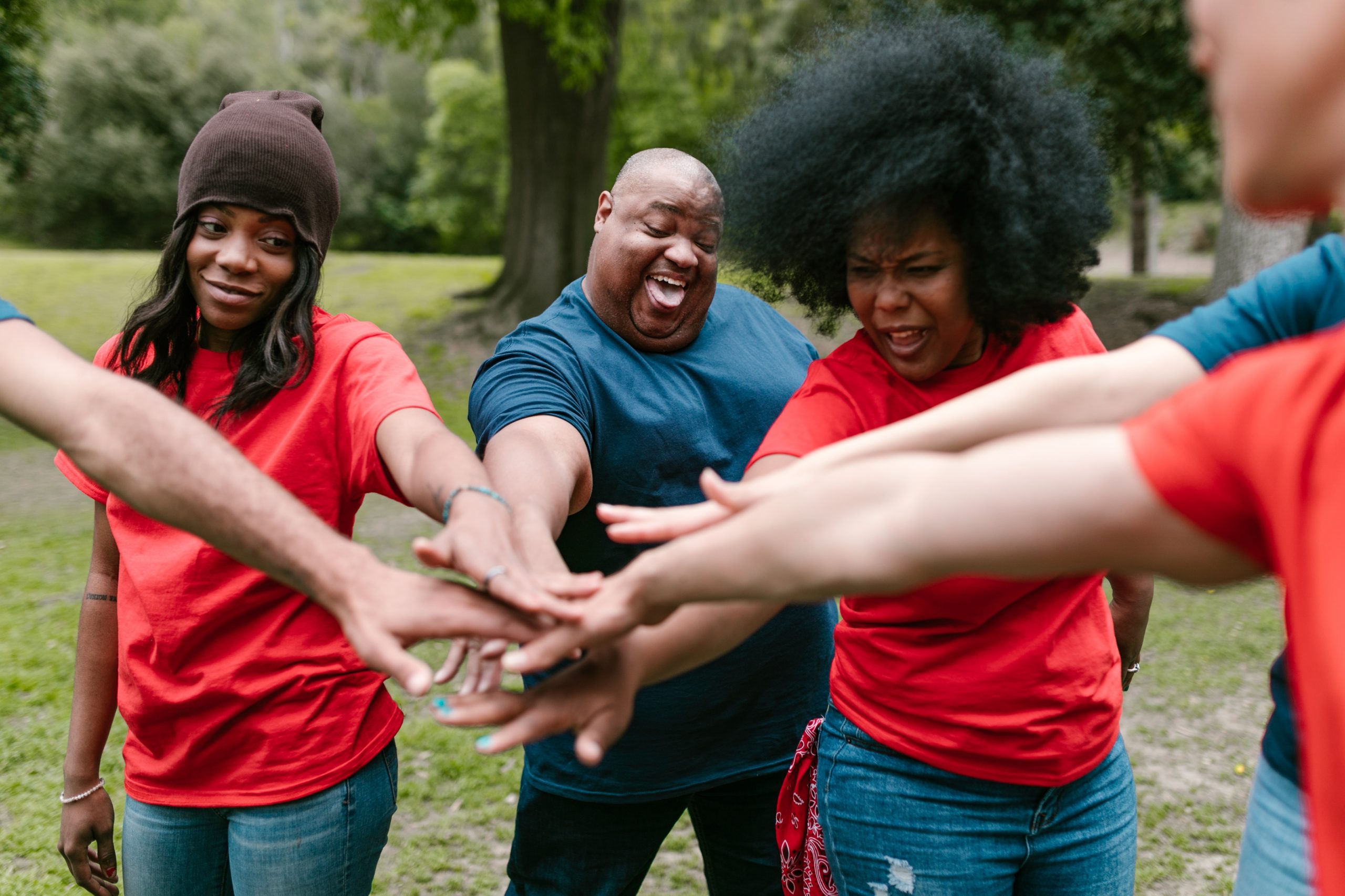 Several people in a circle putting their hands together toward the centre.